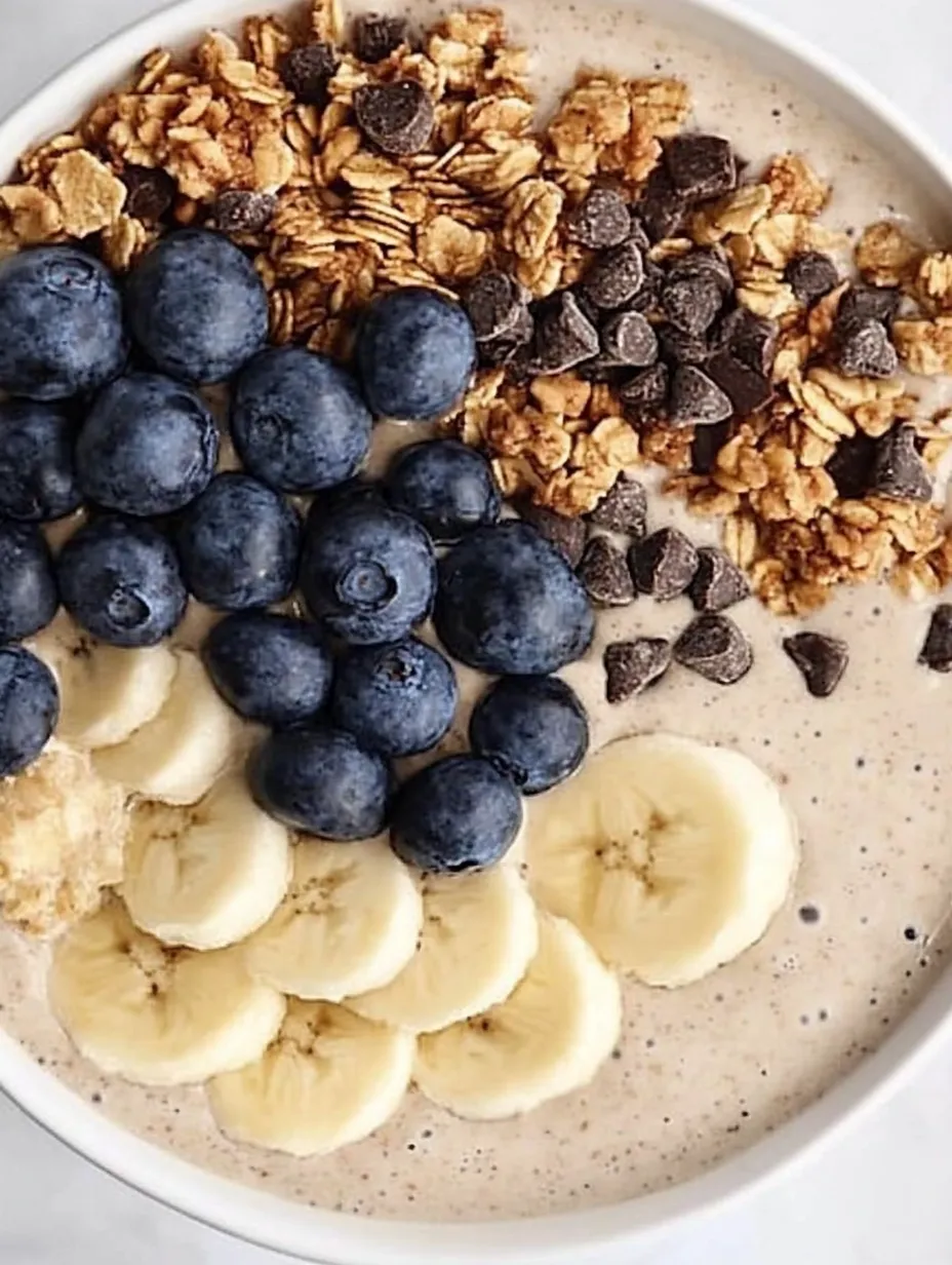 A bowl of cereal with bananas and blueberries.