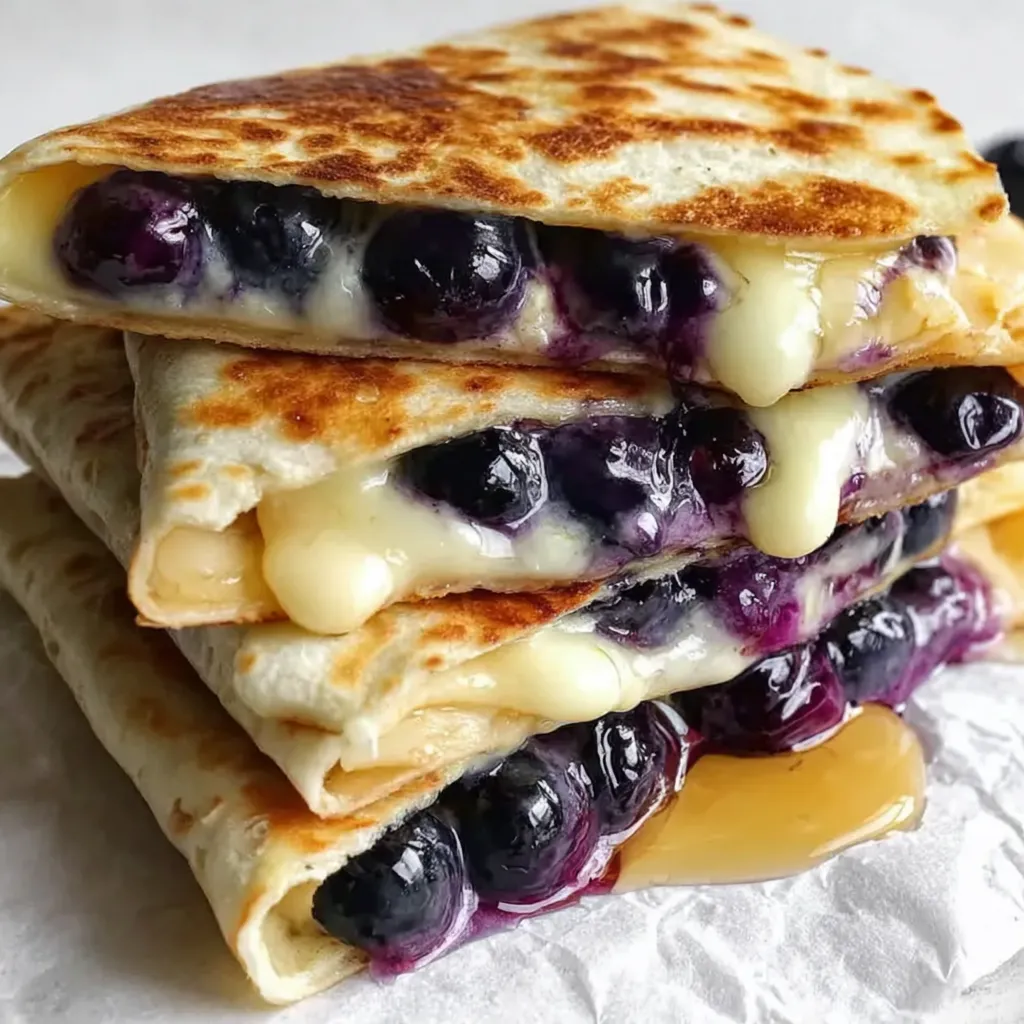 A stack of sandwiches with blueberries and cheese.