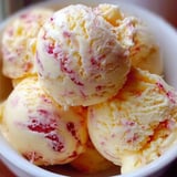 A bowl of ice cream with red and yellow swirls.